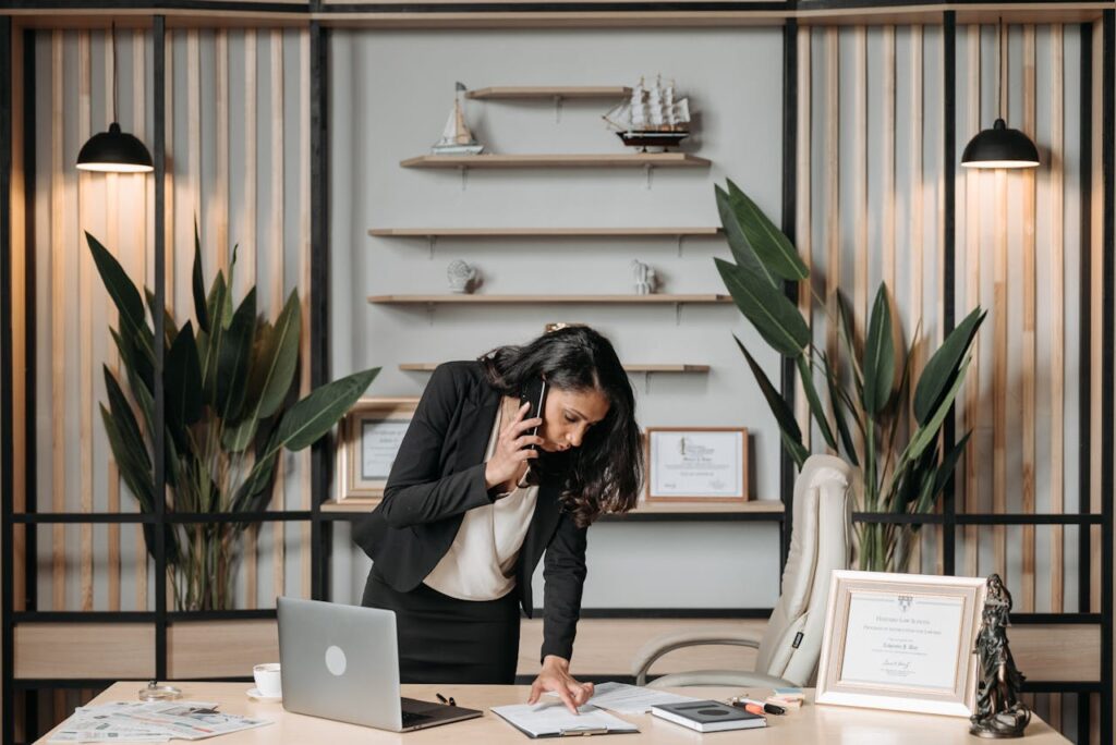Attorney working in a modern office at a boutique law firm, reviewing case notes and speaking on the phone.