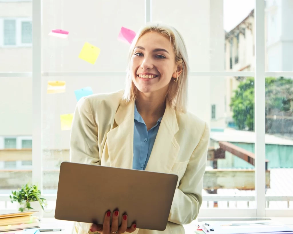 Woman in professional attire holds laptop and smiles - Financial Storytelling for Advisors & Accountants featured image