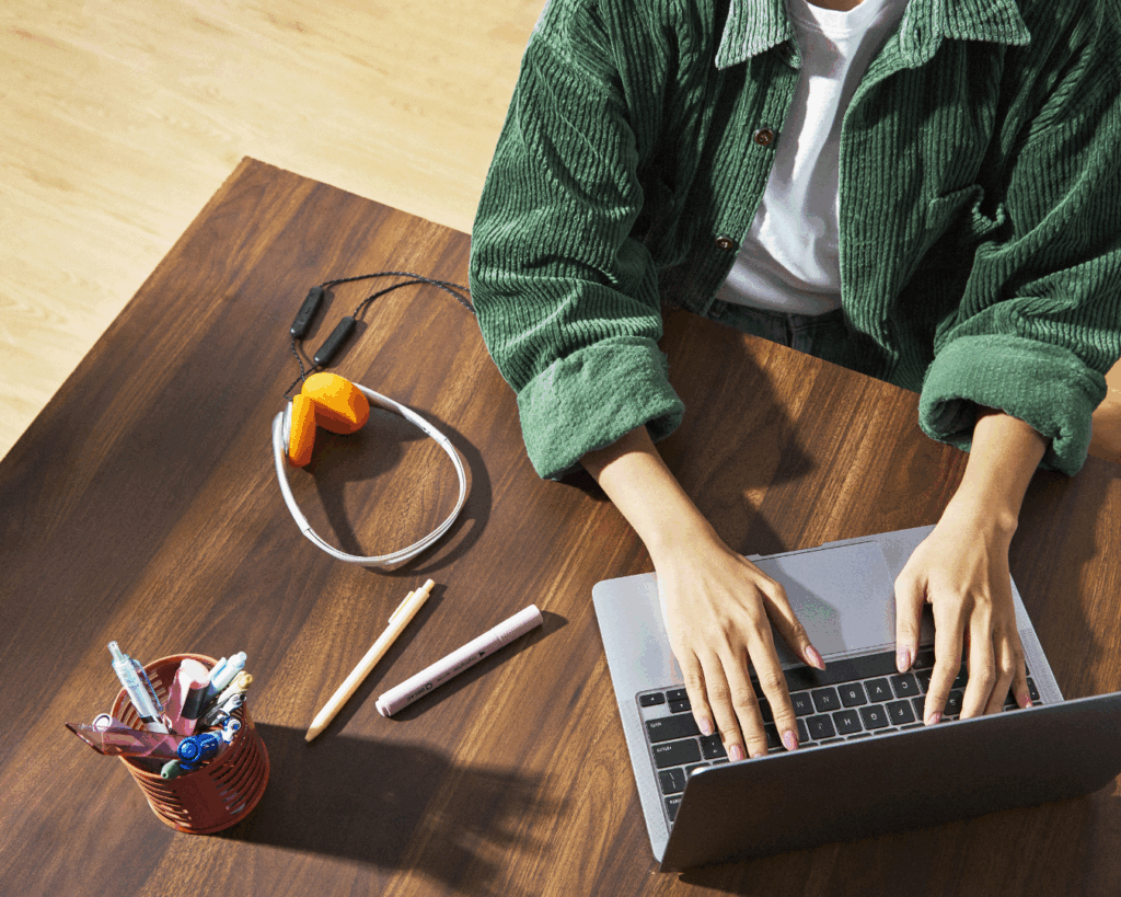 a woman in a green jacket sits at a hip but tidy desk representing brand clarity