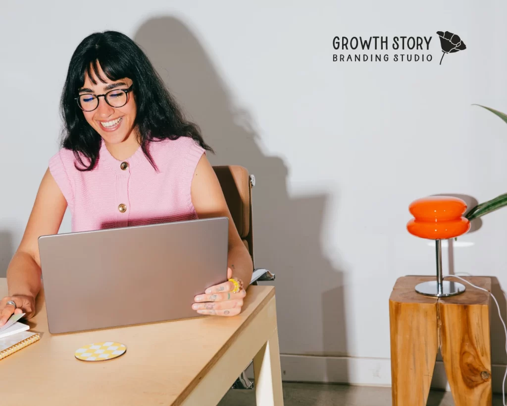 woman in pink sweater at her desk celebrating brand clarity