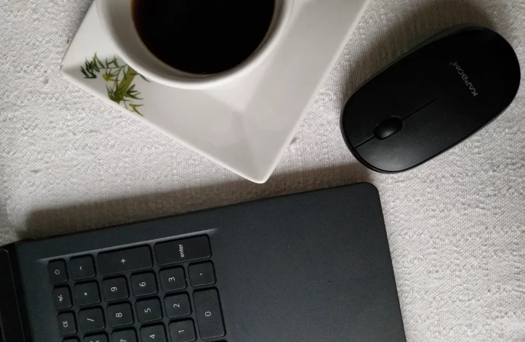Gray laptop, mouse, and cup of coffee on a counter